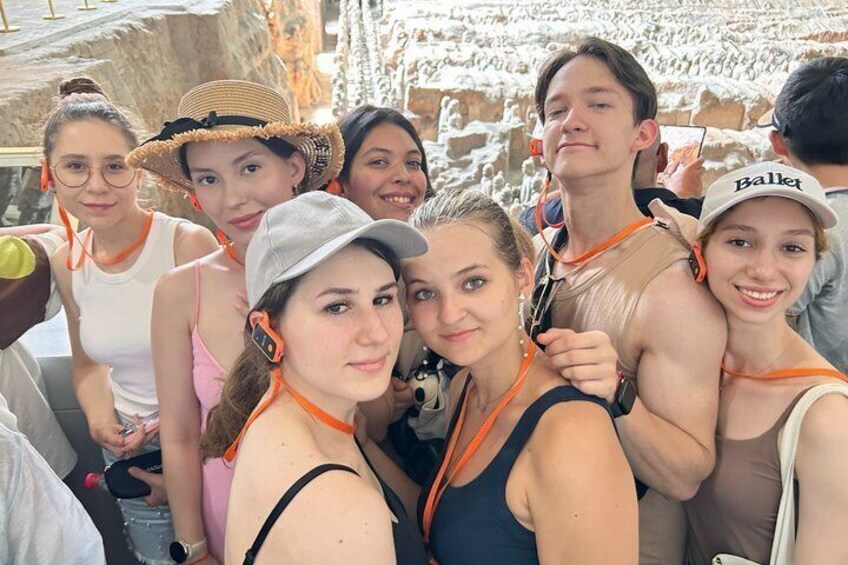 Eine Gruppe von Personen mit orangefarbenen Stirnbändern und Tanktops versammelt sich draußen. 1