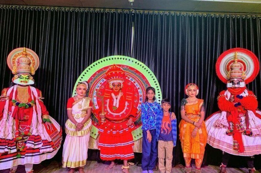 Performers in traditional costumes with elaborate headpieces and a large circular backdrop. 4