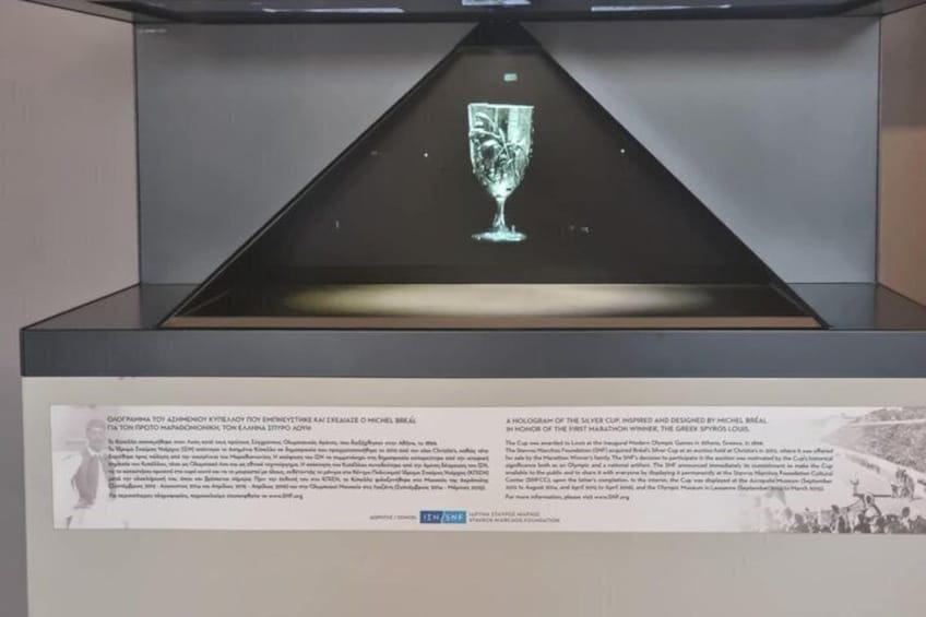 A glass trophy with a holographic design, displayed in a dark case with informational plaques. 2