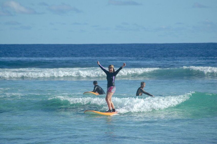 A person surfing on a wave with two other surfers in the background. 5