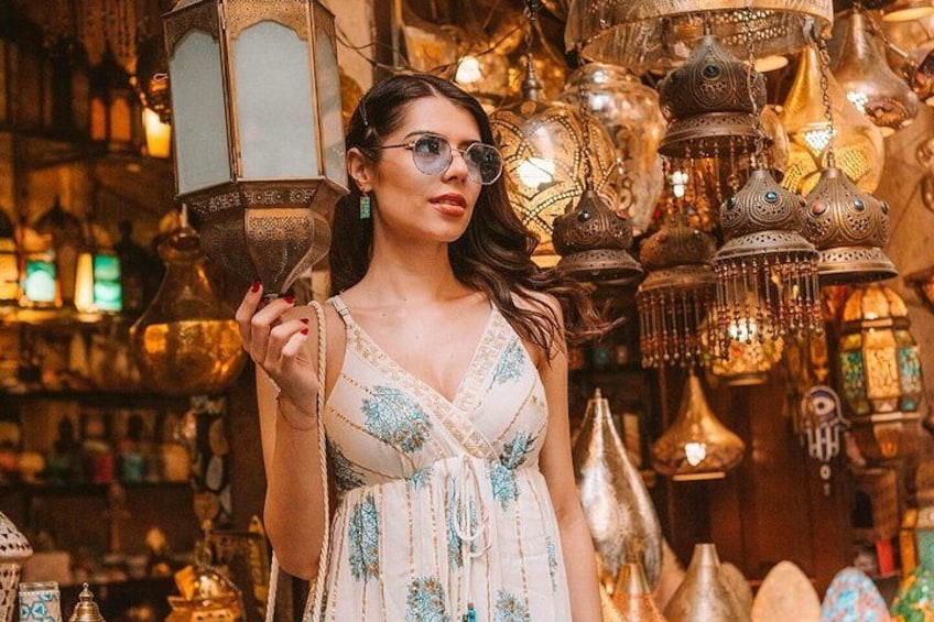 Una persona sosteniendo un farol en una tienda llena de objetos decorativos. 4