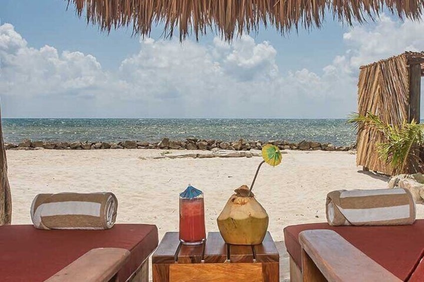 Una spiaggia con lettini, un ombrellone in stile tiki e una bevanda su un tavolo. 5
