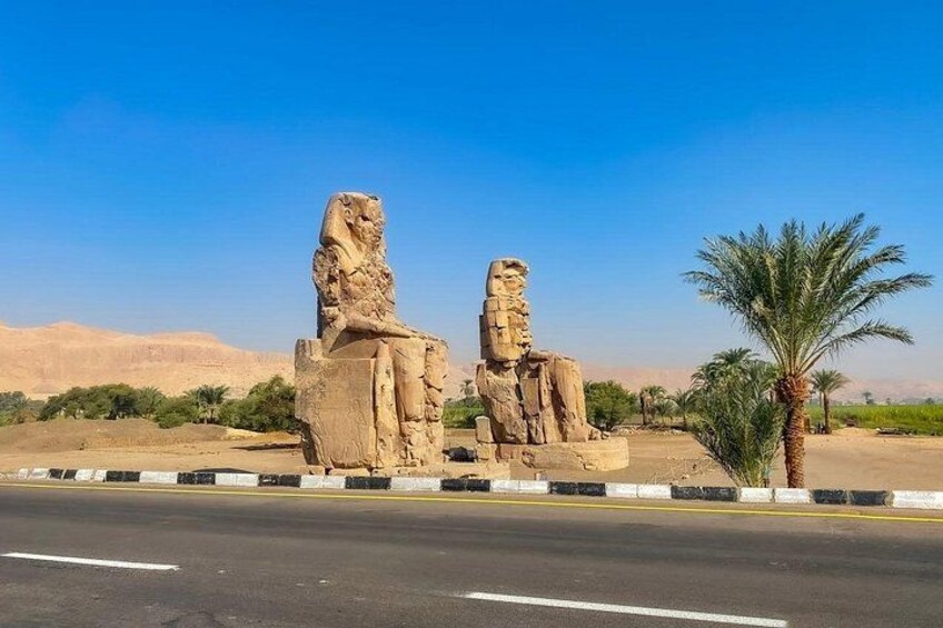 Dos grandes estatuas de piedra en un paisaje desértico con una carretera al frente. 4