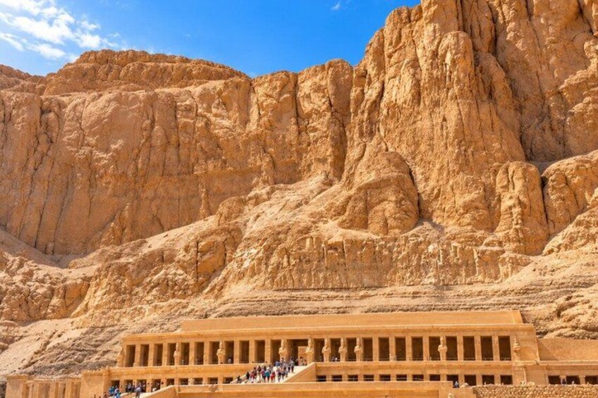 Un'imponente parete rocciosa di arenaria con un tempio alla sua base. 4