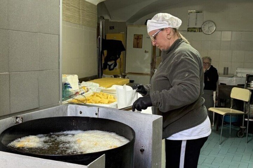 En person som steker mat i en stor stekpanna i ett kök. 4