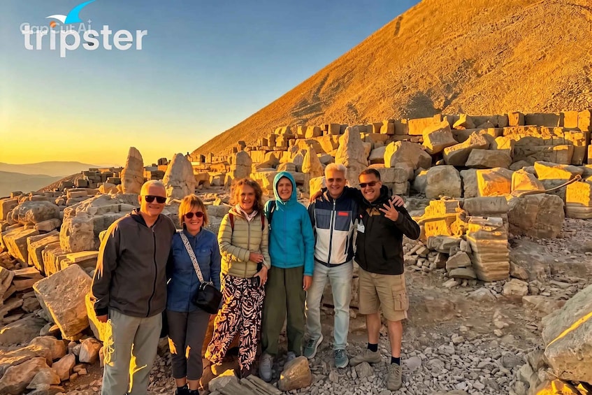 A group of people standing in front of ancient stone structures with a desert landscape in the background. 5
