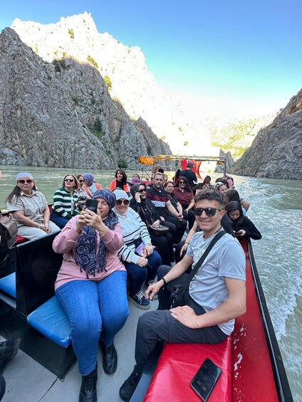 A group of people on a boat tour, surrounded by rocky cliffs and a calm river. 5