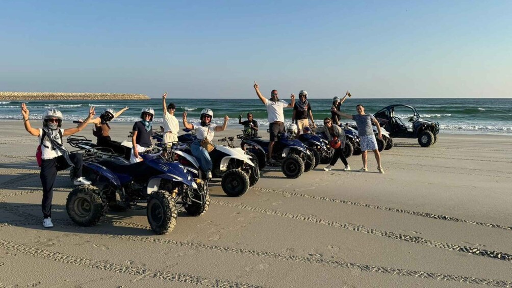 A group of people on a beach with ATVs lined up. 1