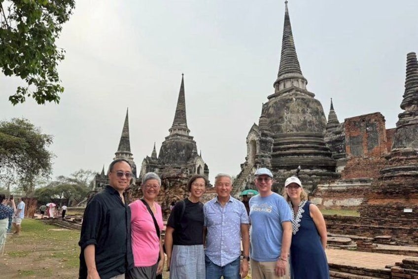 A group of people standing in front of ancient temple structures with multiple spires. 1