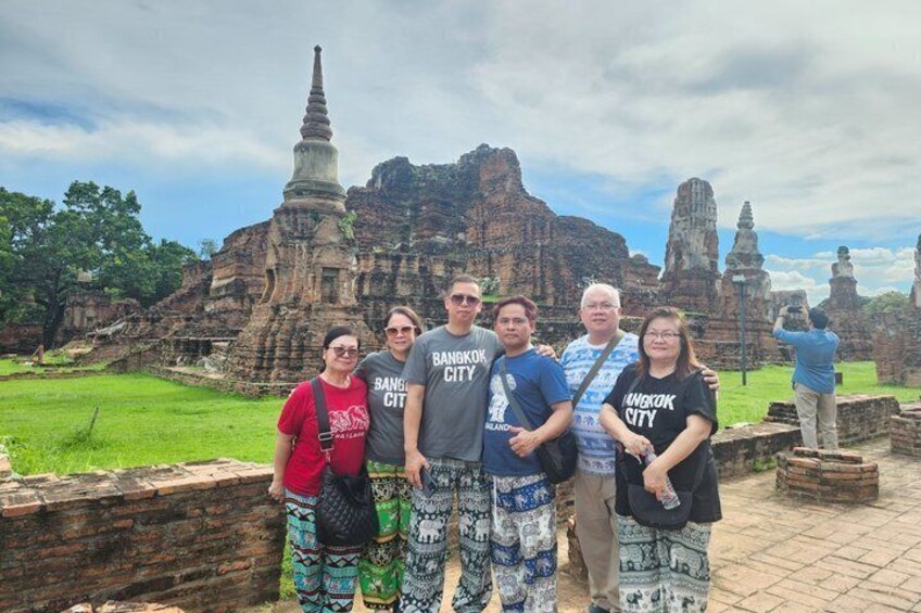 A group of people standing in front of ancient ruins with a stupa and stone structures. 5