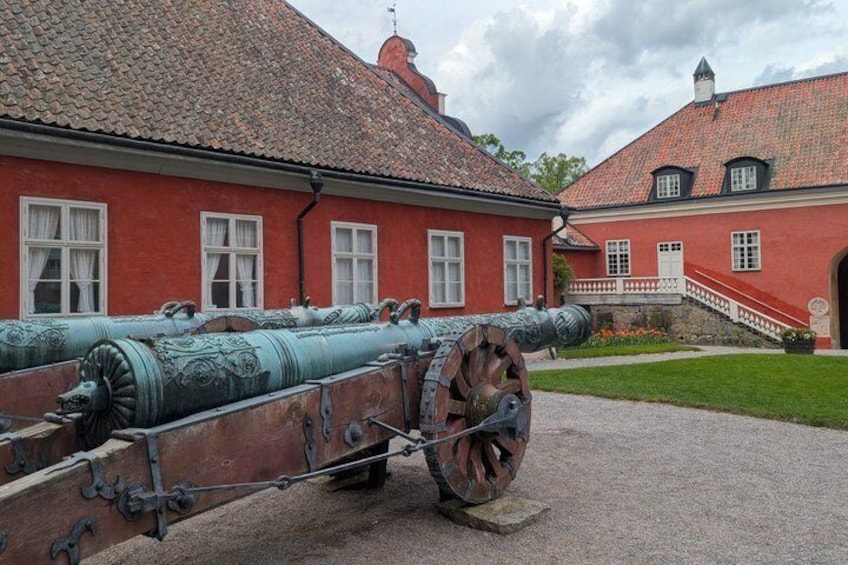 Eine große Kanone vor einem roten Gebäude mit einem Ziegeldach. 4