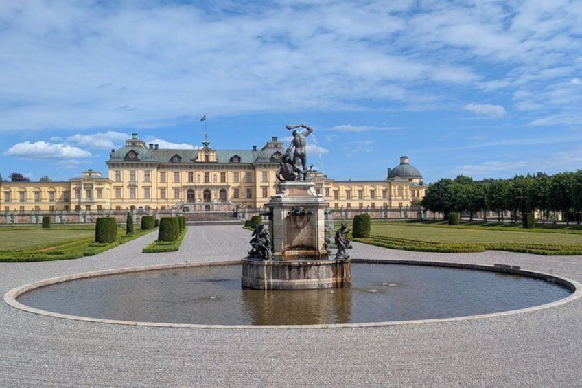 Ein prächtiges Palastgebäude mit einem zentralen Brunnen und gepflegten Gärten. 1