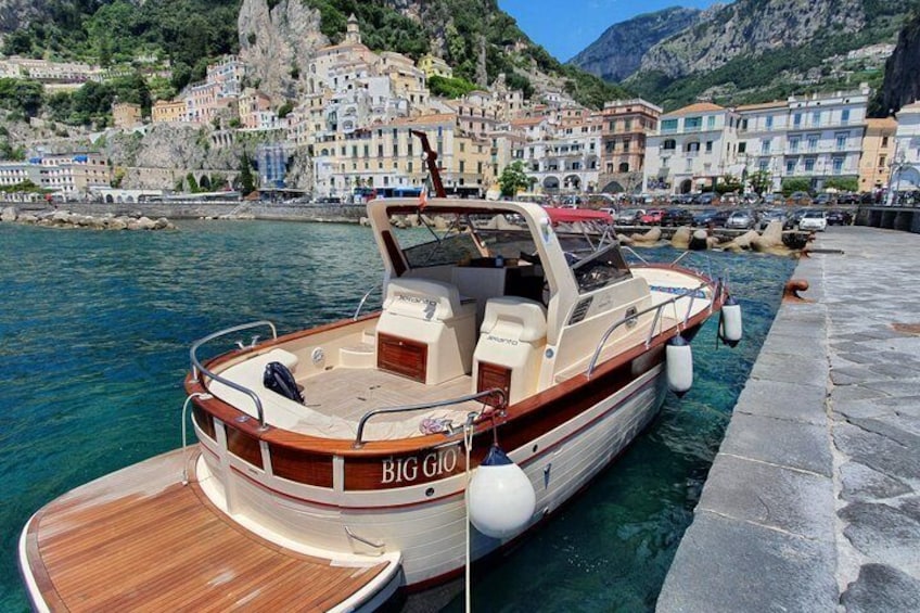 Un barco llamado 'BIG GIO' atracado en un puerto deportivo, con edificios coloridos y un paisaje montañoso de fondo. 3