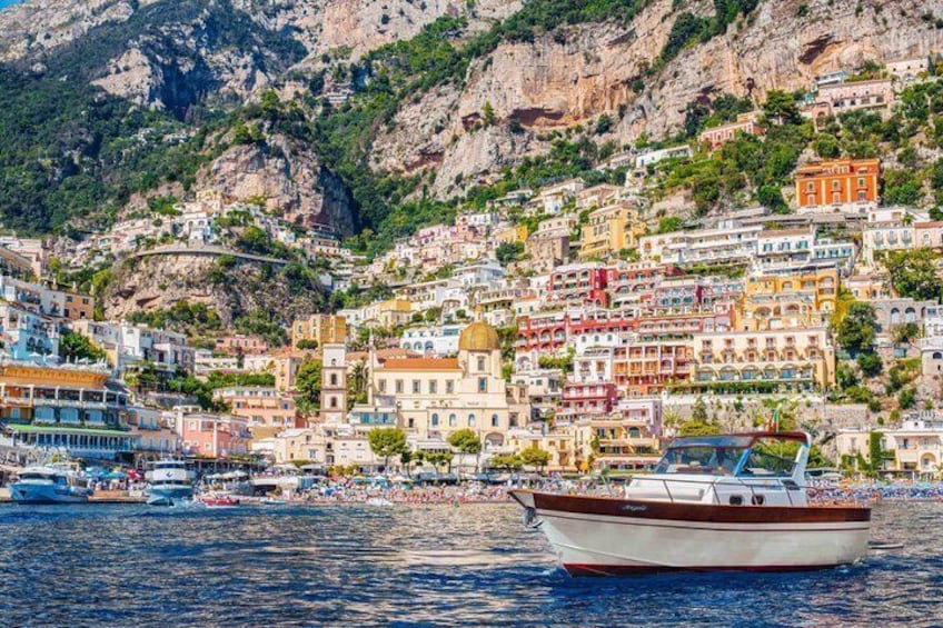 Un pueblo costero con edificios coloridos, un barco en el agua y montañas al fondo. 1