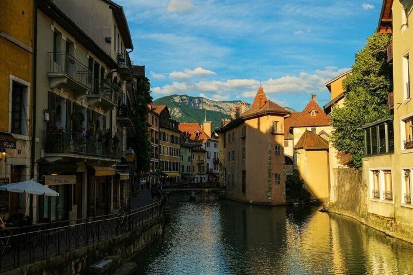 Un canale stretto costeggiato da edifici storici con balconi, con una montagna sullo sfondo. 2