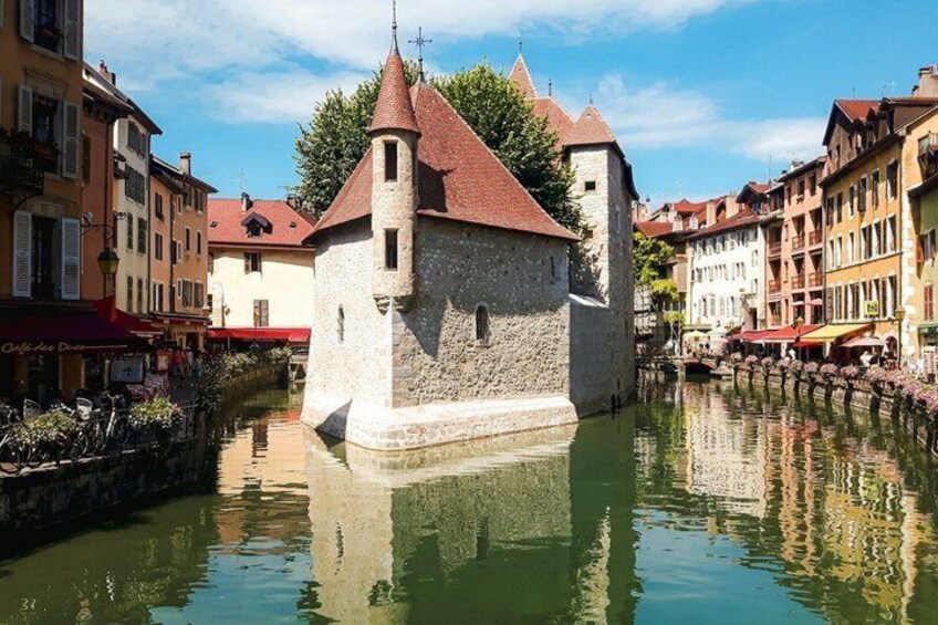 Un'antica torre in pietra con tetto rosso, un canale e edifici colorati lungo la riva. 3
