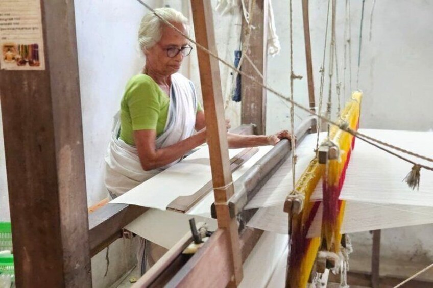 A person weaving on a loom with a white cloth. 3