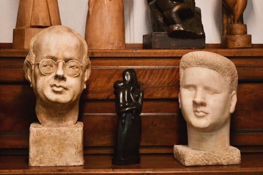 A wooden shelf with three bust sculptures and a small black figurine. 2