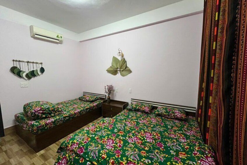 A bedroom with two single beds, a hanging plant, and a patterned curtain. 2