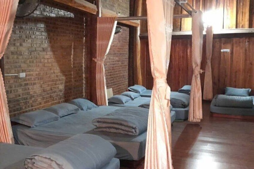 A room with multiple beds, wooden walls, and a brick wall. 3