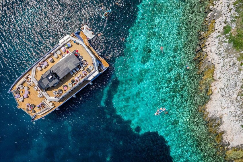A boat docked at a clear turquoise beach with rocky shoreline. 5
