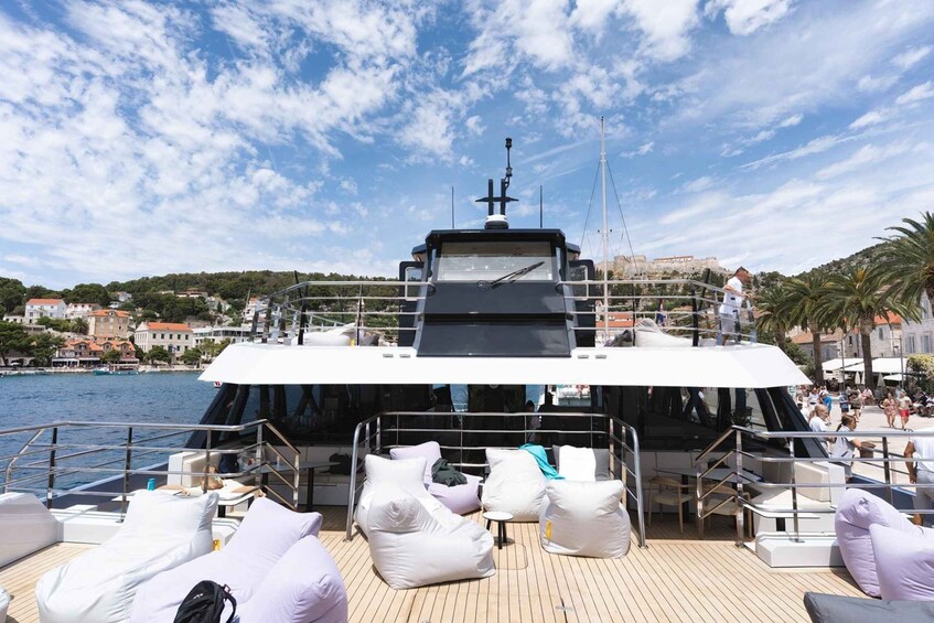 A yacht with a deck lounge area, a helipad, and a view of a coastal town. 3