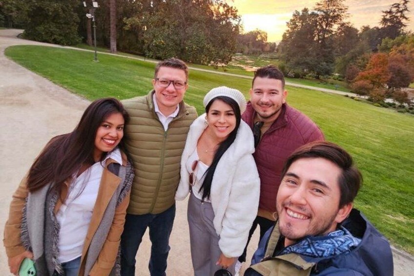 A group of people standing on a path in a park with trees and grass in the background. 2