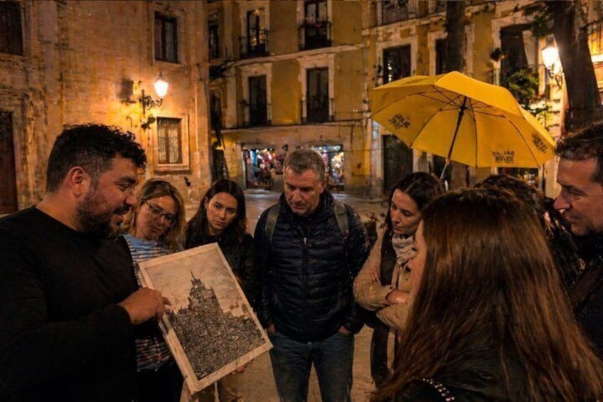 A group of people gathered around a person holding a map in an urban street at night. 1