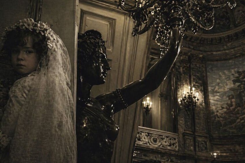 A grand interior with a statue, ornate ceiling, and a mirror. 4