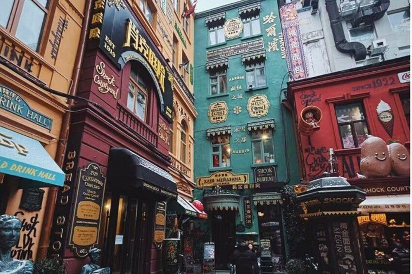 A narrow street lined with colorful buildings, including a shop with a sign that reads 'DREAMER'S BREWERY' and another with 'SHOCK COURT.' 4