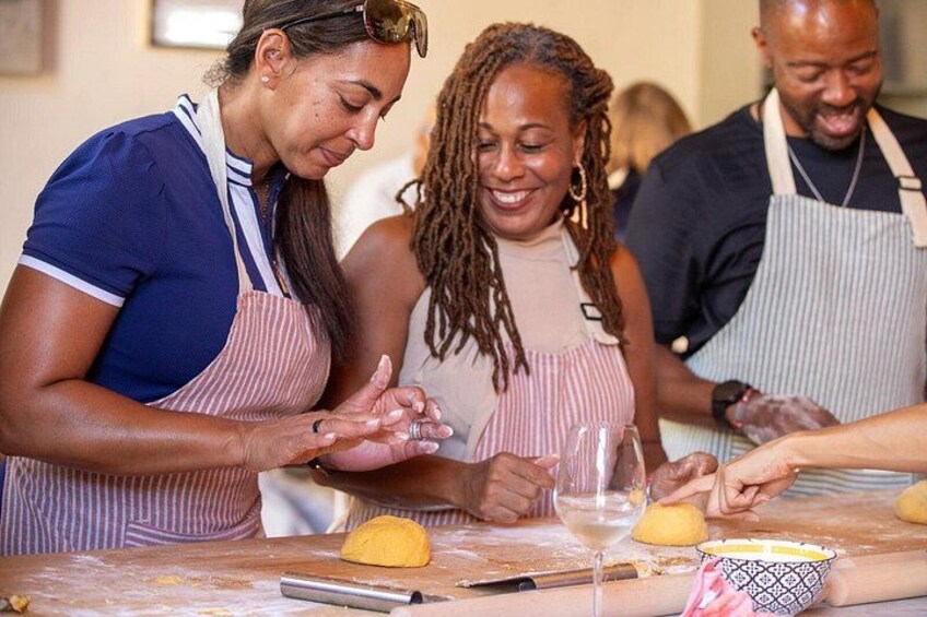People wearing aprons, working with dough on a table. 3