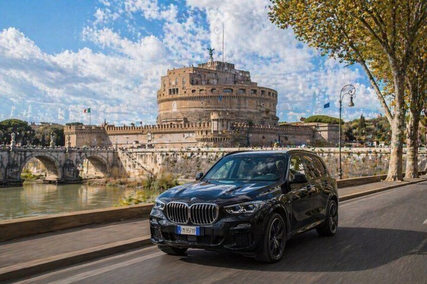 A black car parked on a road with the Colosseum in Rome in the background. 3