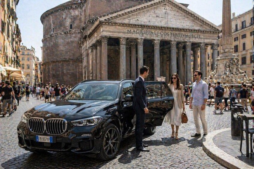 A black BMW parked on a cobblestone street with classical architecture in the background. 1