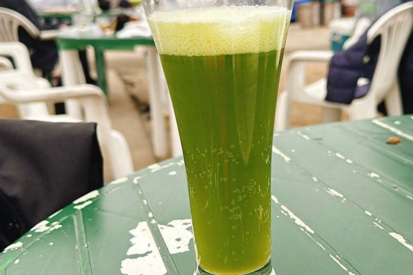 A tall glass of green liquid on a green table. 4
