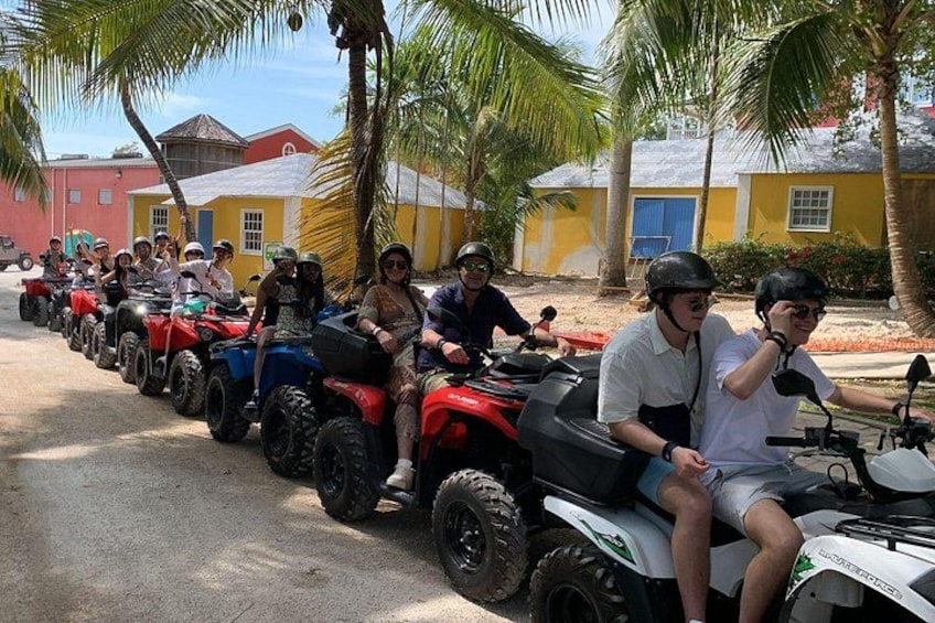 Un grupo de personas paseando en vehículos todo terreno por una calle bordeada de palmeras y edificios de colores. 5
