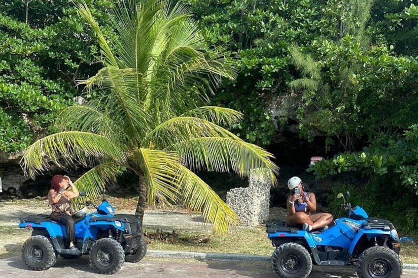 Dos personas en cuatrimotos azules estacionadas cerca de una palmera. 2