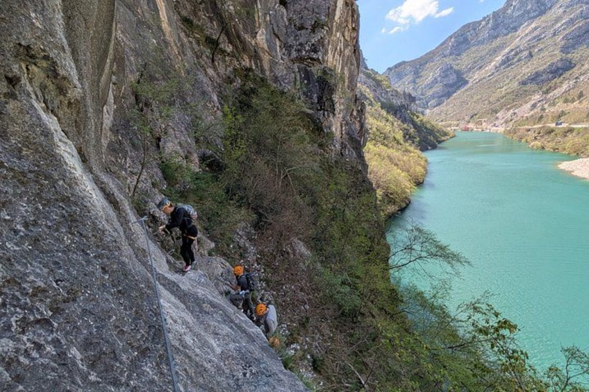 A mountainous landscape with a river, rocky cliffs, and hikers. 5