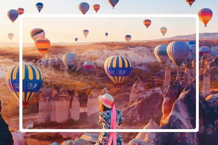 A landscape with hot air balloons, rocky terrain, and a person in the foreground. 2