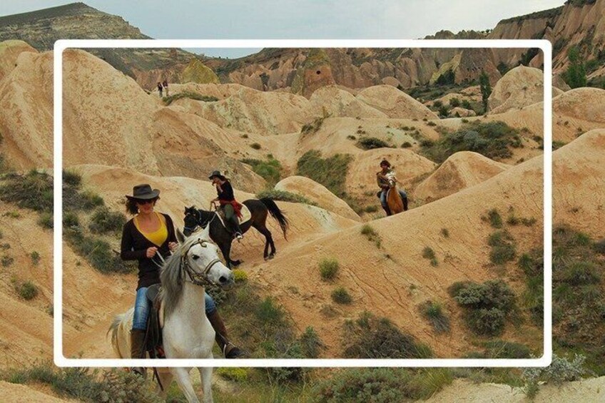 A group of people riding horses in a desert landscape with rolling hills and sparse vegetation. 4