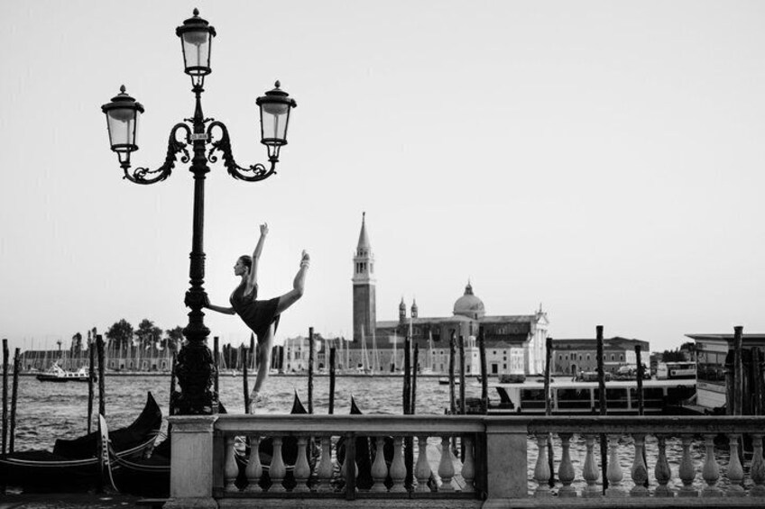 A gondola on a canal, a person performing a trick, and the Torre tower in Venice. 5