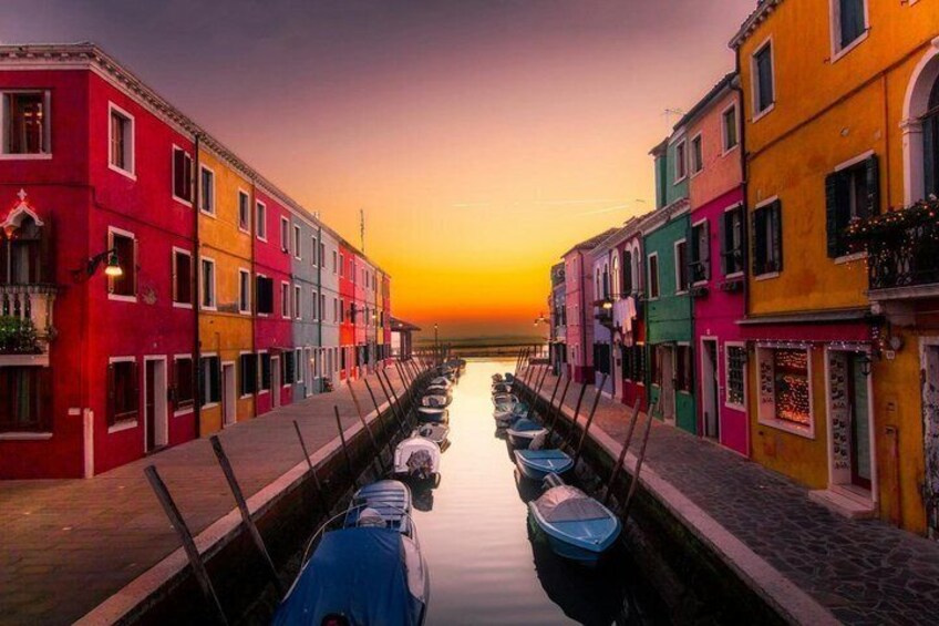 A canal lined with colorful buildings at sunset. 4