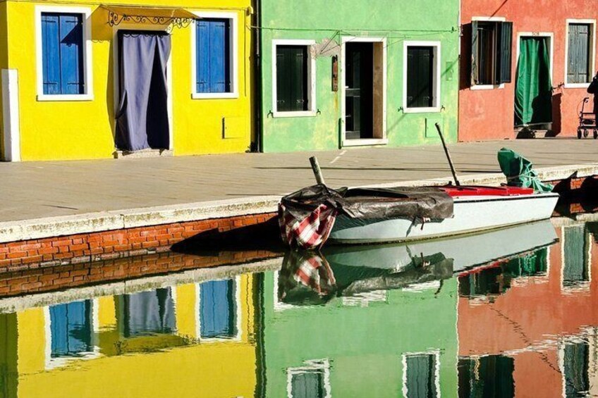A colorful row of buildings with a boat moored at the dock. 2