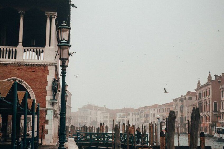 A historic Venetian canal with buildings, a bridge, and a lamppost. 3