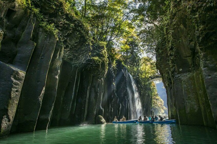 A boat on a river surrounded by tall, narrow rock formations with waterfalls. 4
