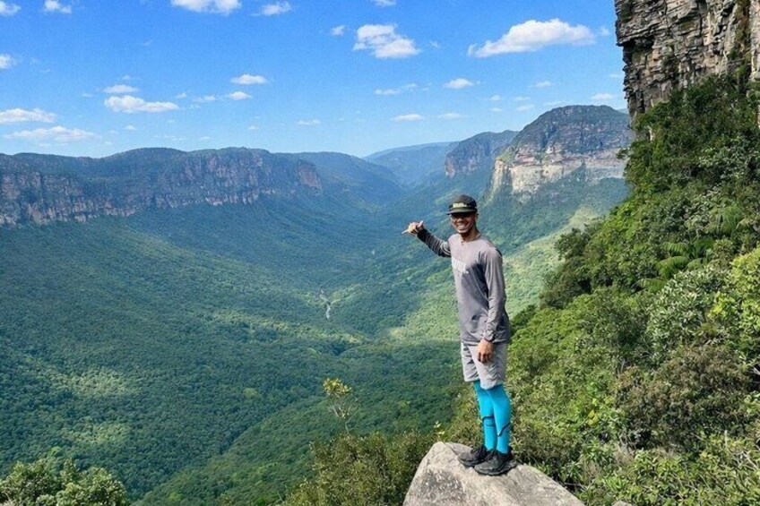 Eine Person steht auf einem Felsen, im Hintergrund eine Berglandschaft. 1
