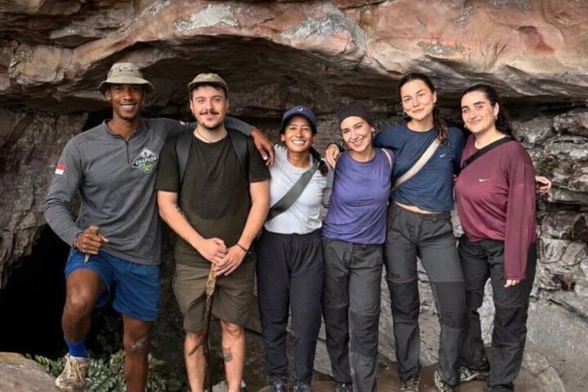 Eine Gruppe von Menschen steht vor dem Eingang einer felsigen Höhle. 3