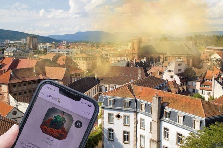 A smartphone displaying a person in a green outfit with a red background, held in front of a cityscape with red-roofed buildings and a church. 1