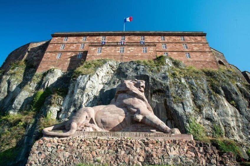 A large building with a statue of a lion on a rocky outcrop. 5