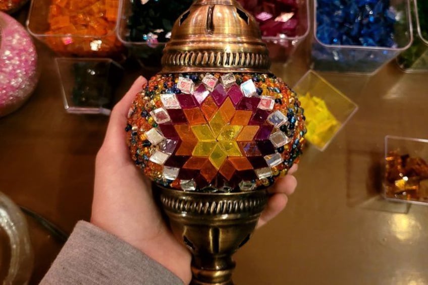 En hånd holder en dekorativ lampe med et mønstret glasafdækning. 4
