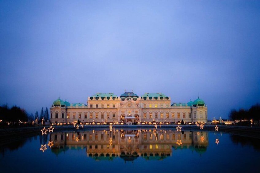 A large, illuminated building with green domes, reflecting in a calm body of water. 5